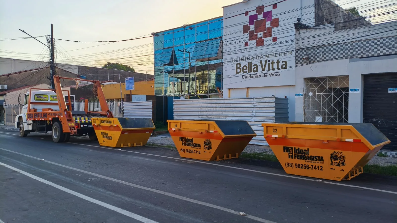 Caçambas de entulho laranja da Ideal Ferragista na rua em frente a lojas em Santa Inês-MA